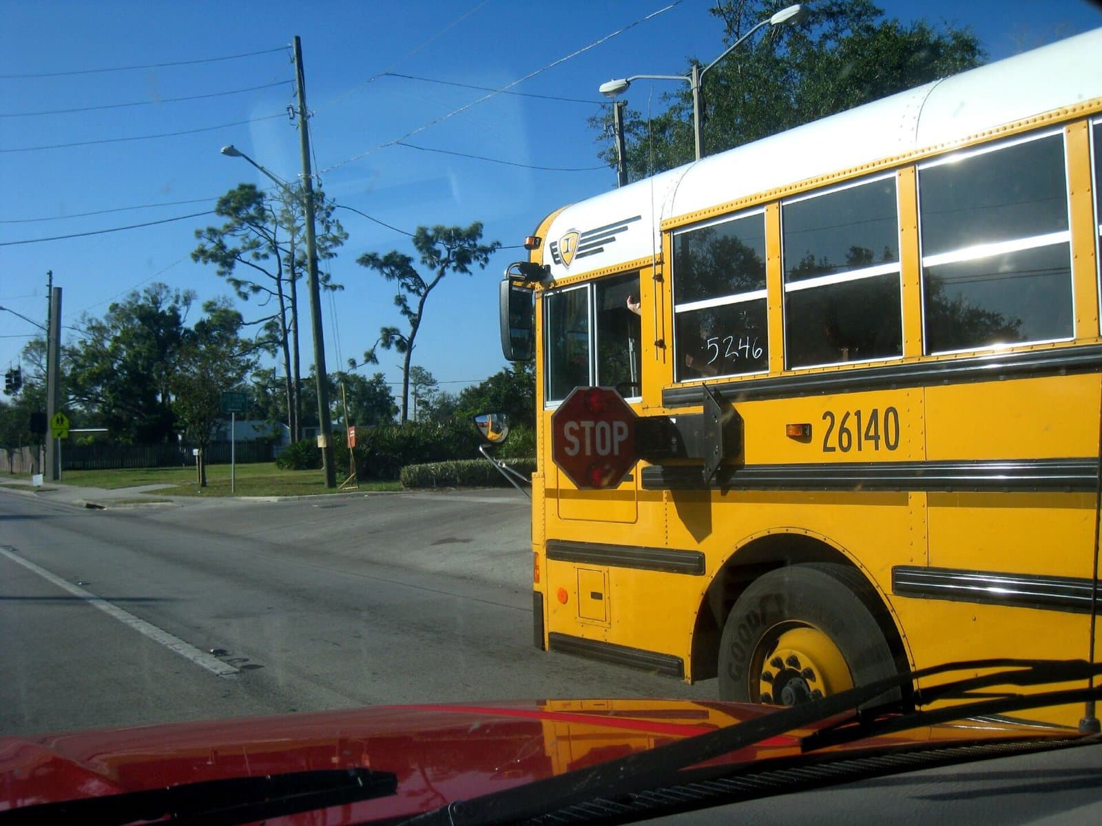 A yellow school bus with its red stop arm extended, seen from a car's driver's seat on a sunny street in Orlando, Florida, November 6, 2008. Illustrative image, not the St. Paul bus. Photo: Katy Warner, CC BY-SA 2.0, via Wikimedia Commons. Source page: https://commons.wikimedia.org/wiki/File:Schoolbusstoparm.jpg